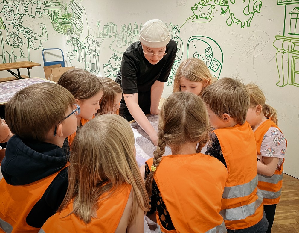 Kinder mit Warnwesten um einen Tisch versammelt beim Workshop "Zukunftskneterei".