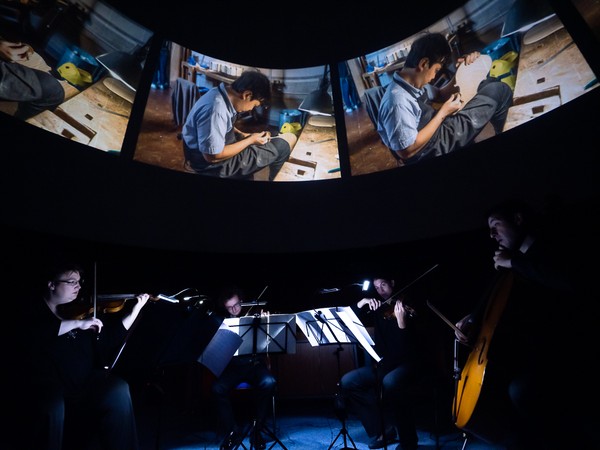 Begleitendes Orchester bestehend aus vier Personen mit Saiteninstrumenten vor der Planetariumskuppel.