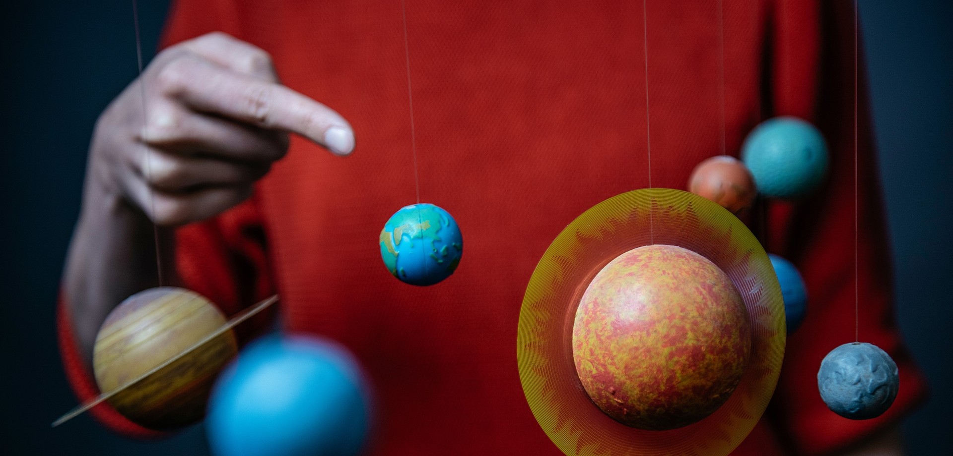 Der Finger einer Person zeigt auf kleine Planeten-Modelle. Foto: LWL