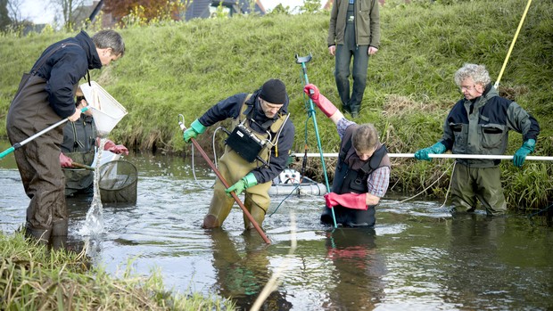 Menschen beim Keschern im Fluss stehend.