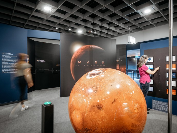 Ausstellungsbereich zum Planeten Mars mit einem Modell des roten Planeten. Foto: LWL/Steinweg (vergrößerte Bildansicht wird geöffnet)