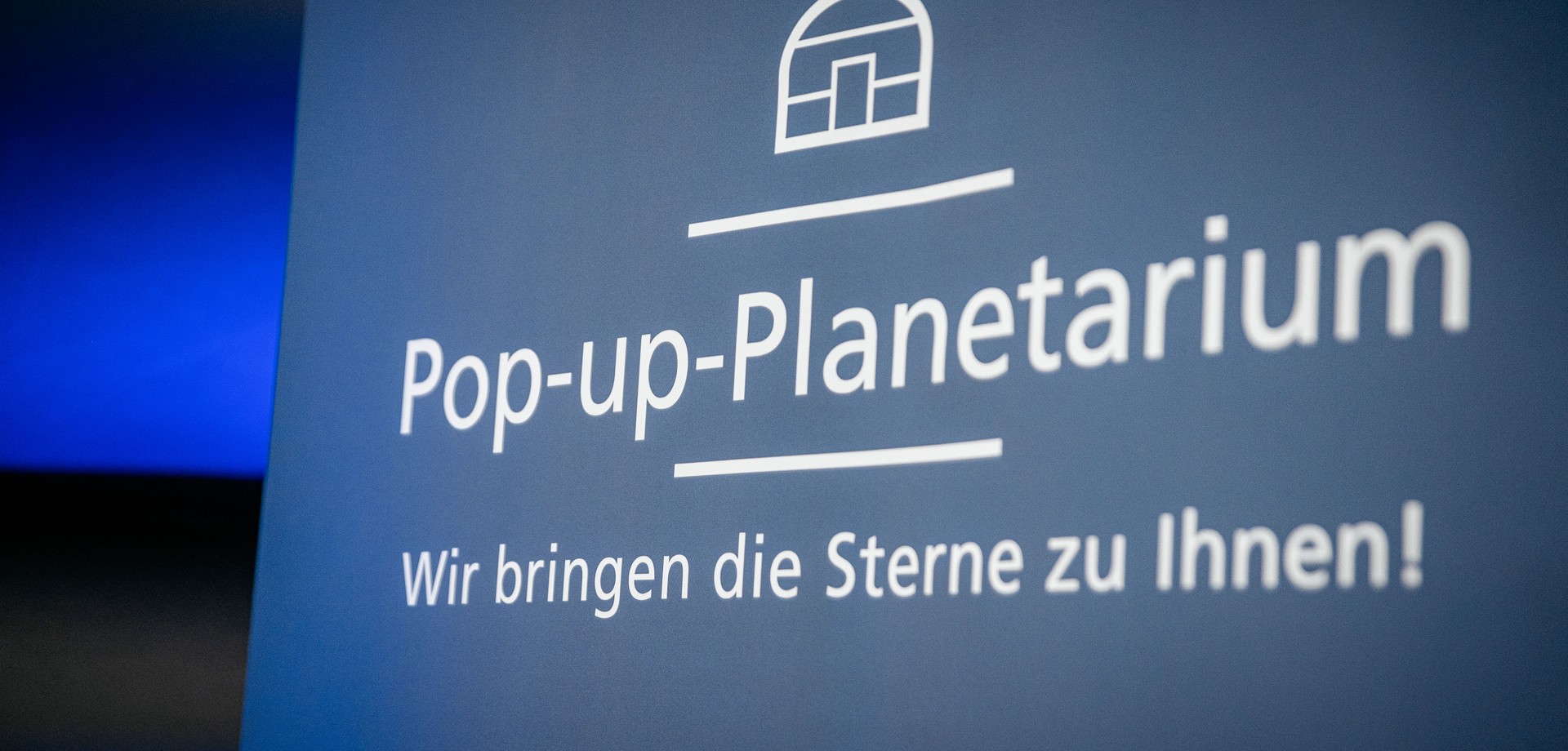 Schriftzug mit Icon eines Planetariums und Text: Pop up Planetarium. Wir bringen die Sterne zu ihnen!