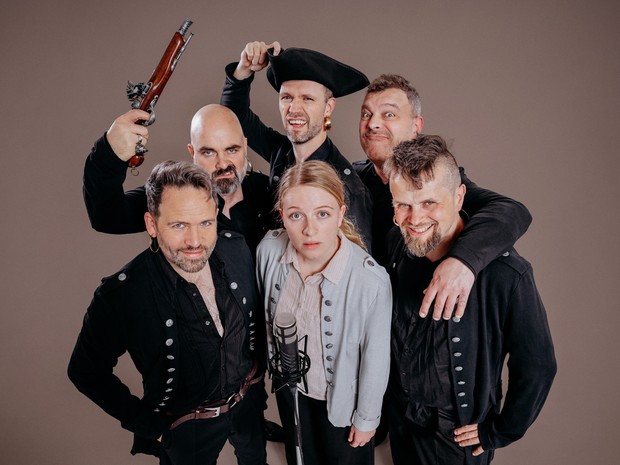 Mitglieder des Theaters ex Libris stehen als Piraten gekleidet vor einem Mikrofon.