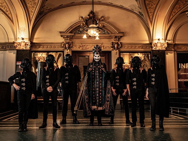 Mitglieder der Band stehen in einem historischen Gebäude.