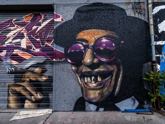 Wandbilder eines rauchenden, lachenden Mannes mit Sonnenbrille und Hut. Foto: Heinrich Brinkmöller-Becker (vergrößerte Bildansicht wird geöffnet)