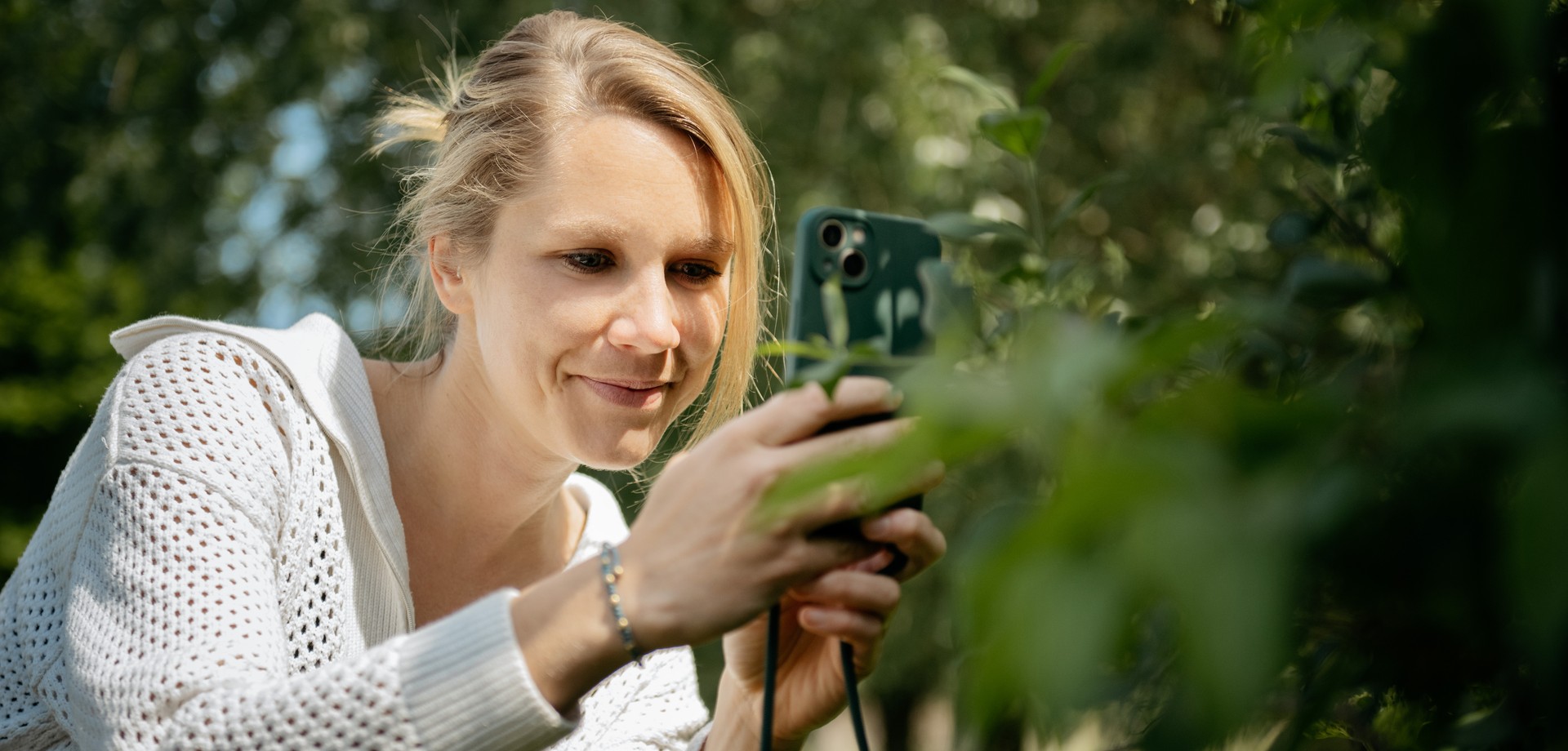 Eine Frau erforscht mit einem Mobiltelefon die Natur.