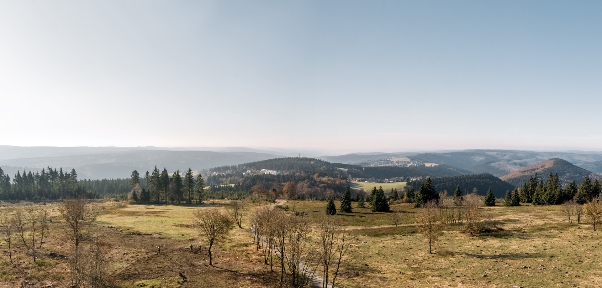 Blick über ein weites Tal vom Berg "Kahler Asten" aus über Heidefläche, Wanderwege und baumbewachsenen Bergen.