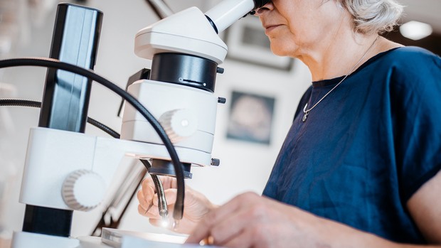 Wissenschaft - Frau schaut in ein Mikroskop