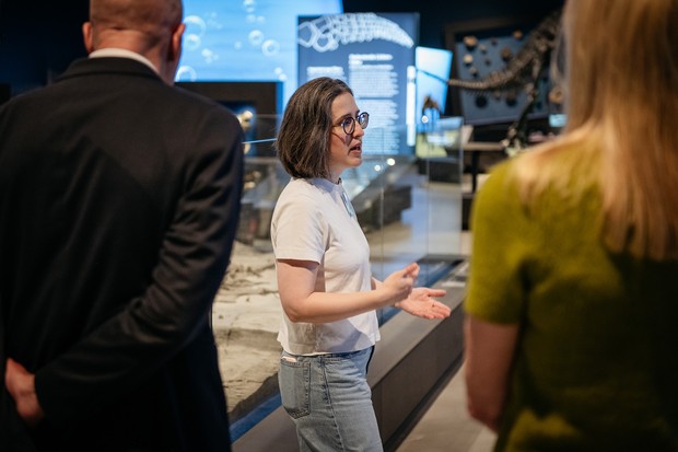 Een museumdocente vertelt een groep volwassenen iets over de tentoonstelling