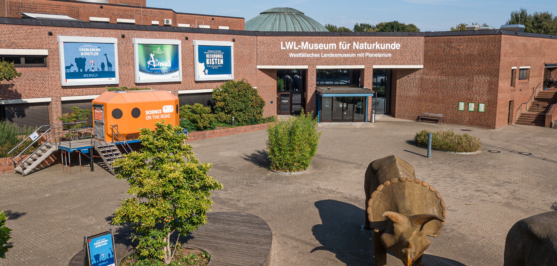 Museum with surrounding green spaces and the objects on the forecourt.