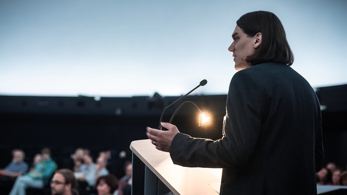 Referent spricht am Stehpult vor Zuschauern im Planetarium. Foto: LWL/Steinweg