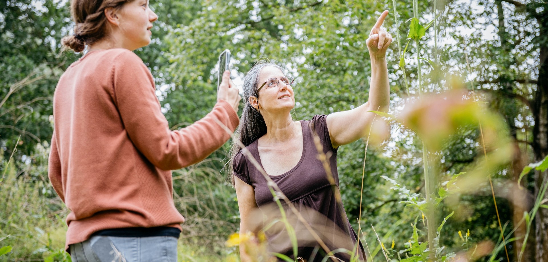 Zwei Frauen erforschen mit einem Mobiltelefon die Natur.