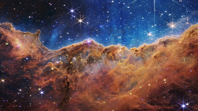 Die „Cosmic Cliffs“, Carinanebel, etwa 8.000 Lichtjahre von der Erde entfernt. Das Bild zeigt erstmals bisher unsichtbare Bereiche der Sternentstehung