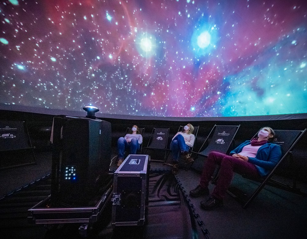 Menschen sitzen im Pop-up-Planetarium und schauen in die Kuppel.