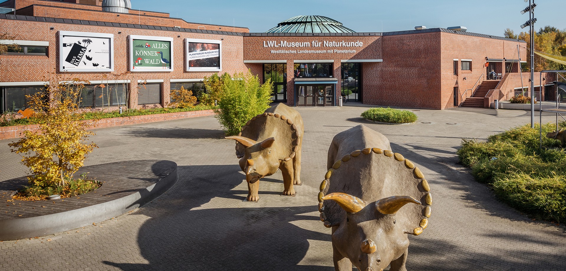 Der Museumsvorplatz mit zwei Dinosauriern.